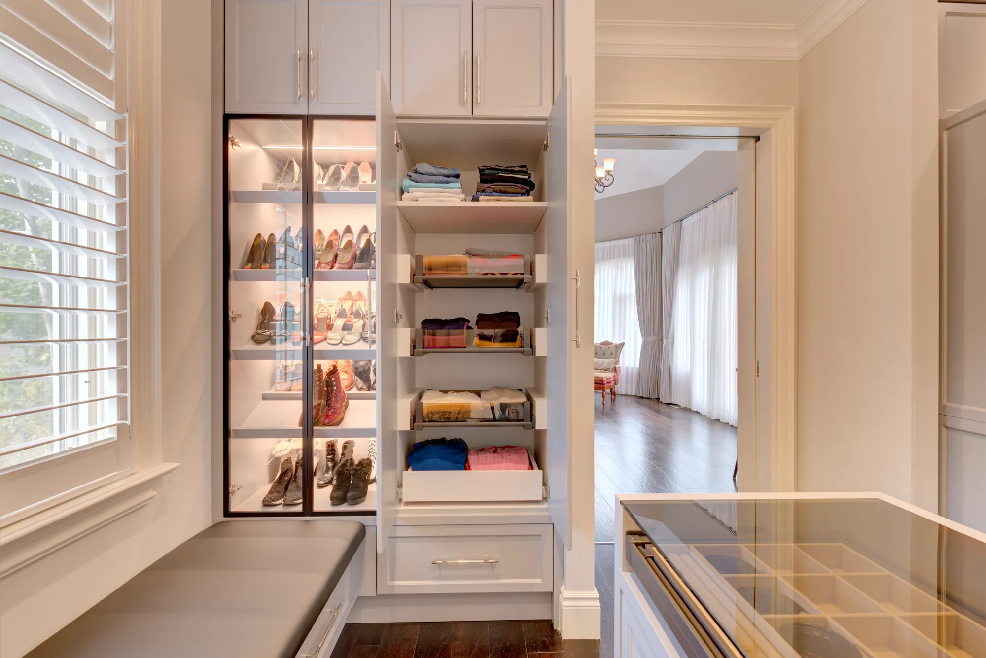Glass-door shoe cabinet beside pull-out shelves in a Richmond Hill dressing room