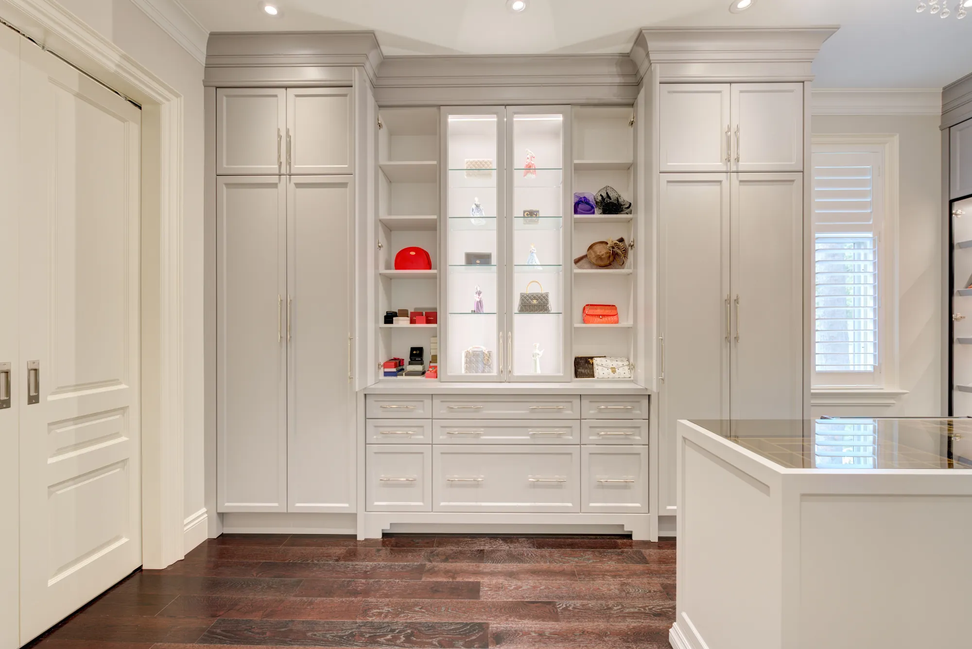 Dressing room with lit glass display cabinet, drawers, and island in Richmond Hill