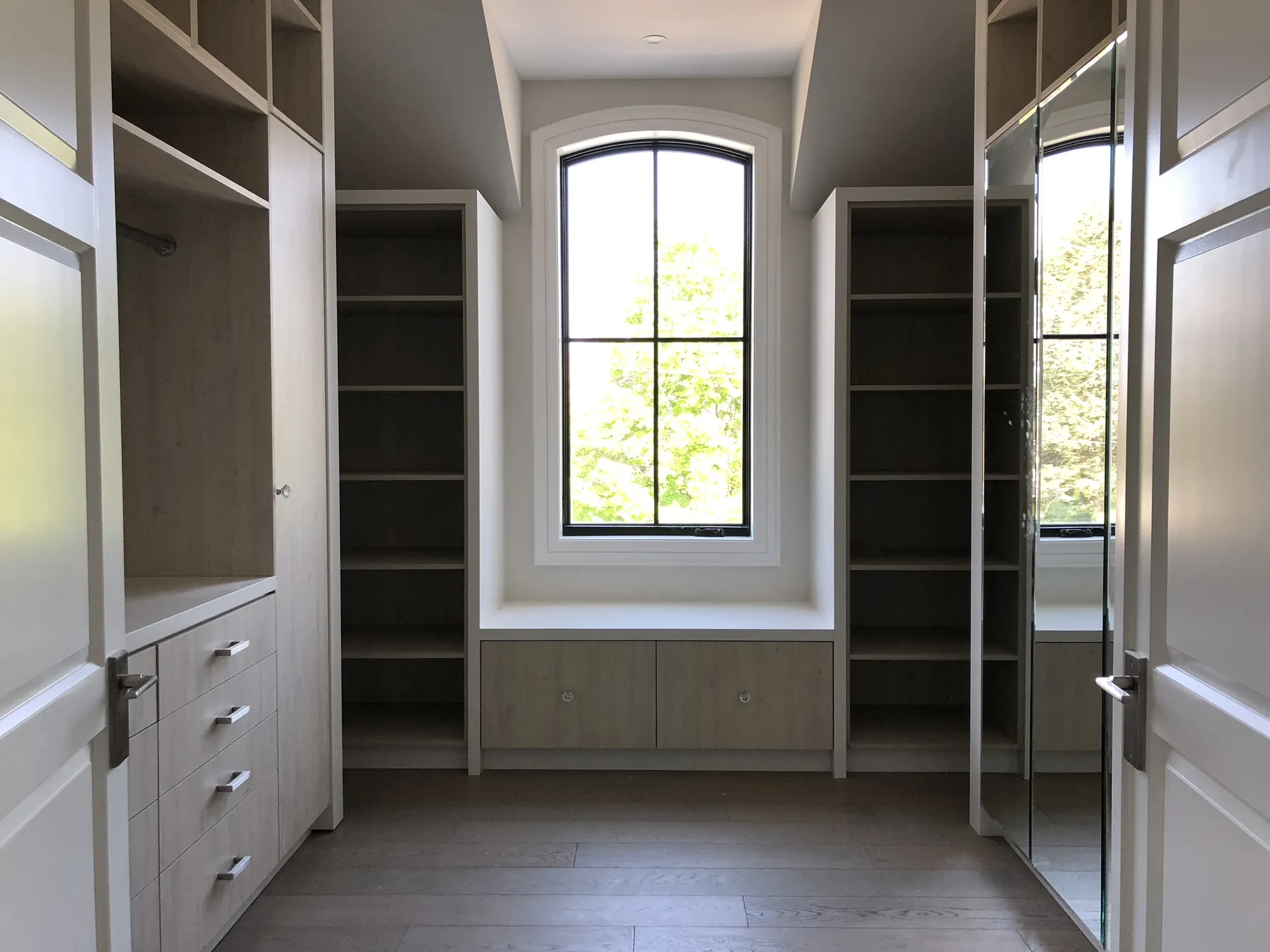 Walk-in closet with window seat and open shelf towers in Toronto